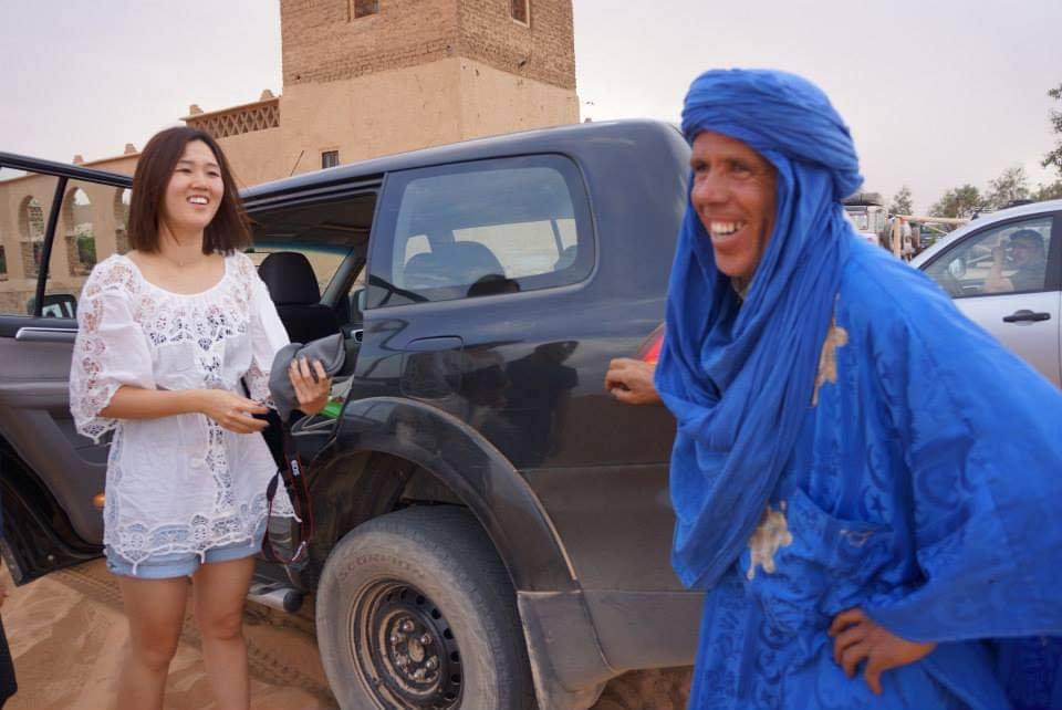 Japanese tourists arriving in a 4x4 off-road vehicle at the edge of the Erg Chebbi sand dunes in Merzouga, southern Morocco, ready to explore the vast Sahara Desert landscape.